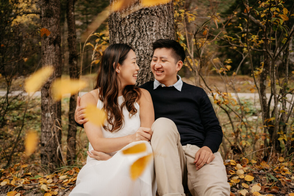 Couple smiling under autumn trees.