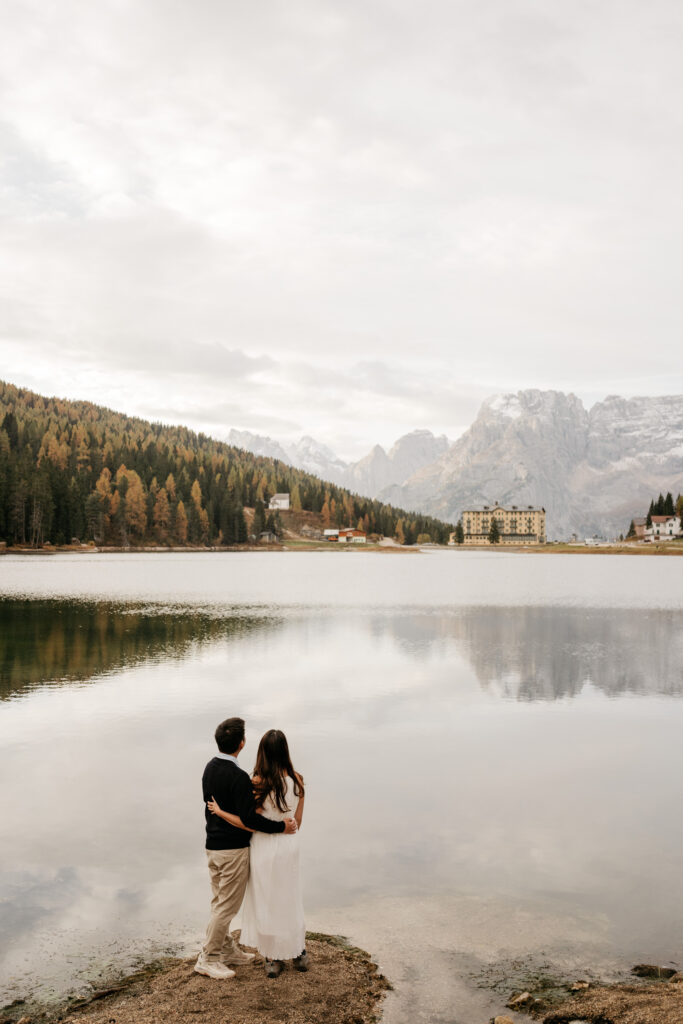 Couple embracing by a serene mountain lake.