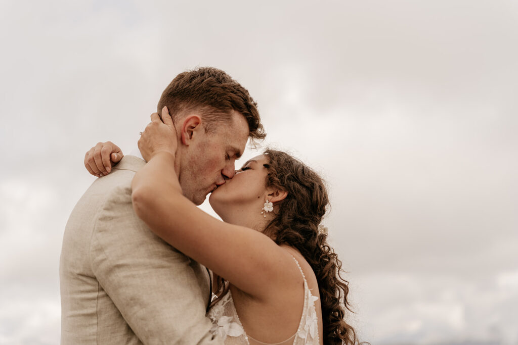 Couple kissing outdoors under cloudy sky