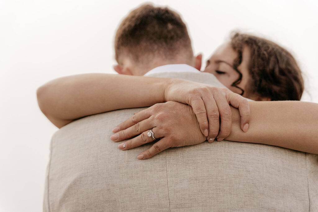 Close-up of couple hugging, woman's hand with ring.