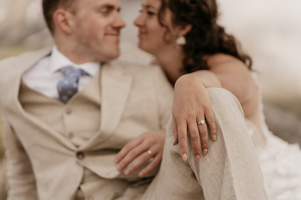 Couple sitting, focus on hand with wedding ring.