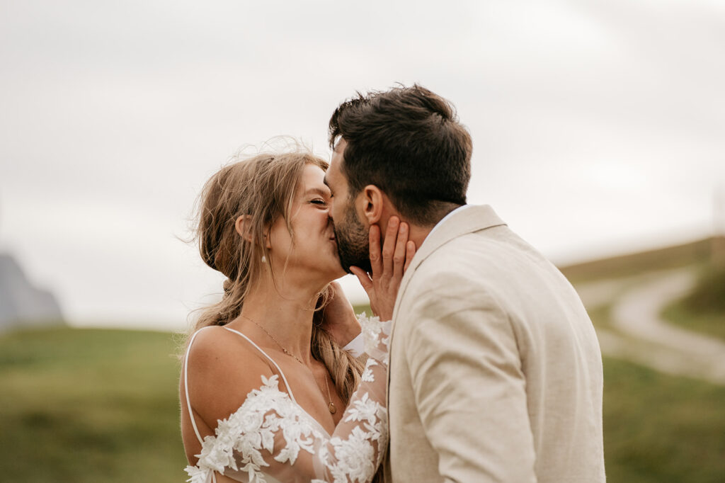 Bride and groom kiss in scenic landscape