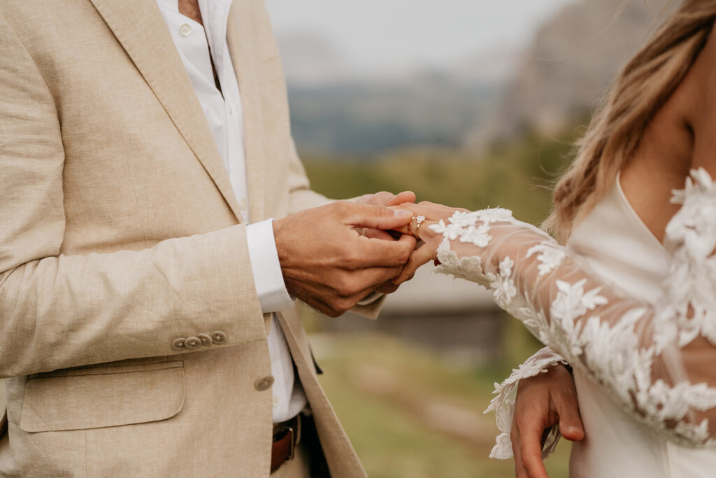 Bride and groom exchanging wedding rings outdoors.