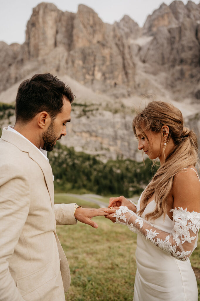 Couple exchanging rings in mountain setting.