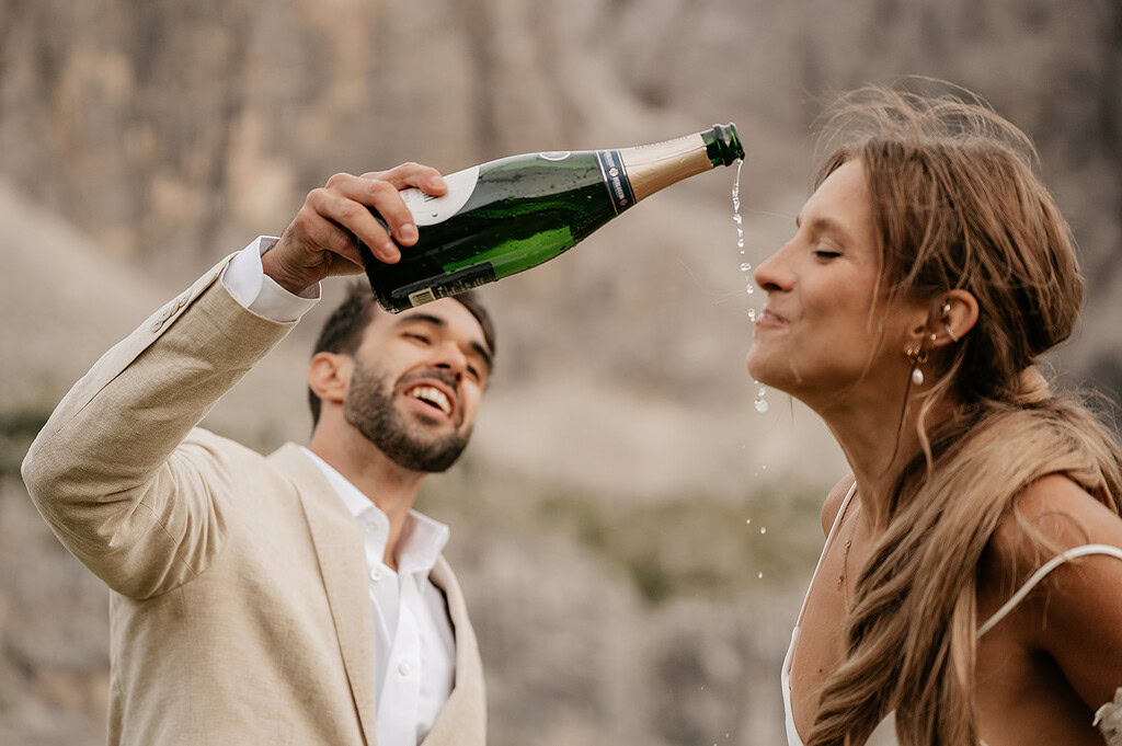 Smiling couple celebrating with champagne outdoors.