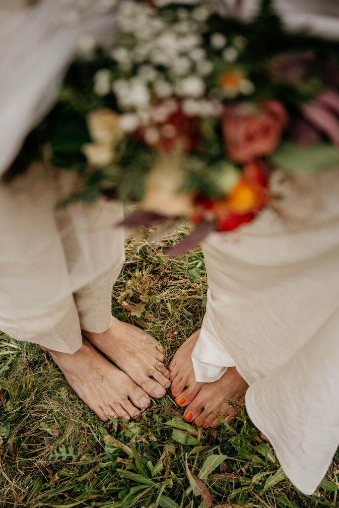 Barefoot couple standing on grass with floral bouquet