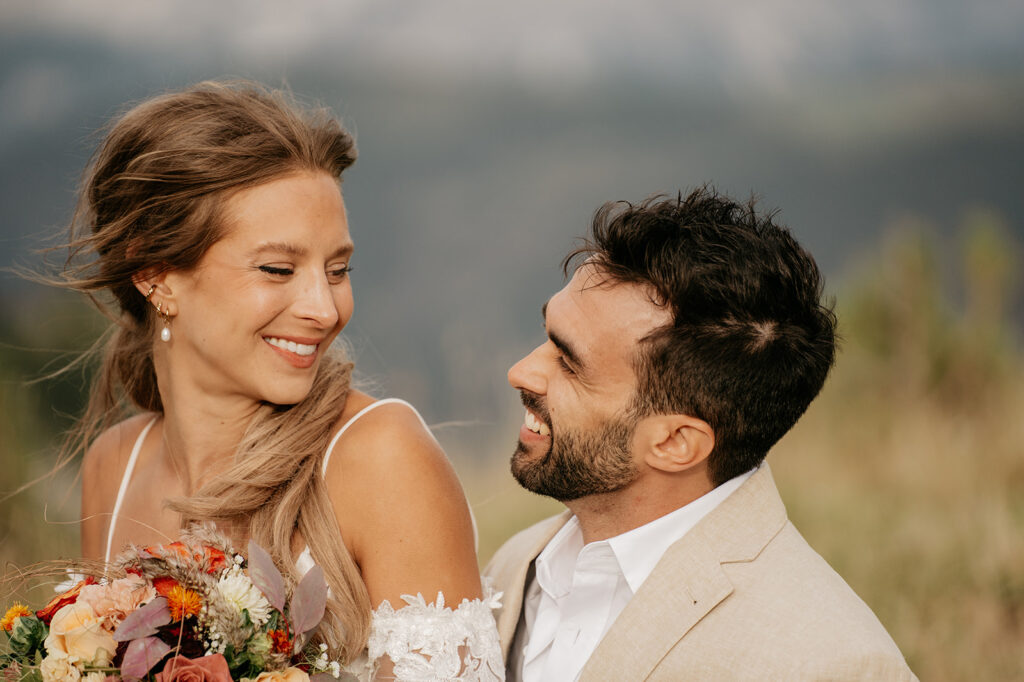 Smiling couple on wedding day with bouquet.