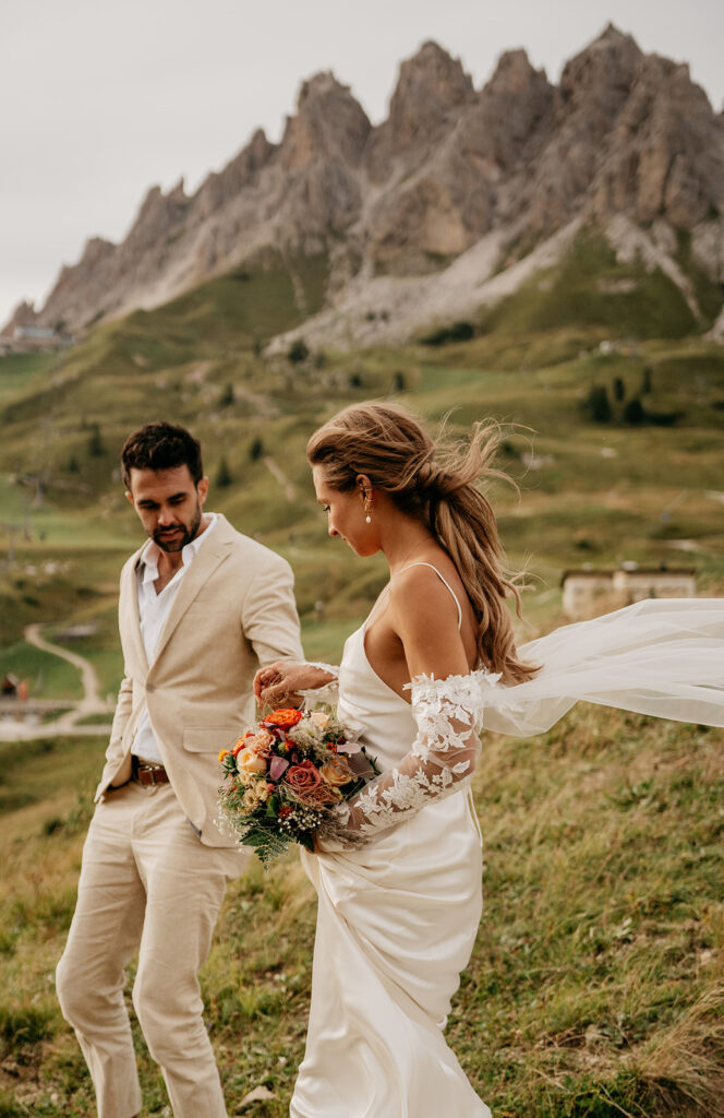 Bride and groom walking in scenic mountain landscape.