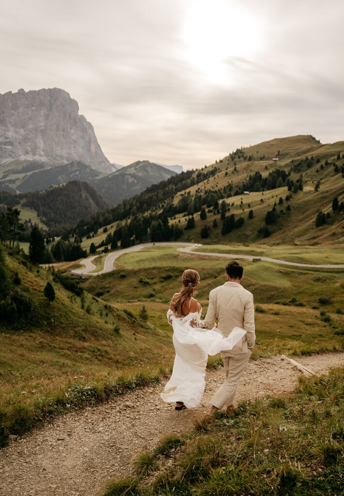 Couple walking on mountain trail at sunset.