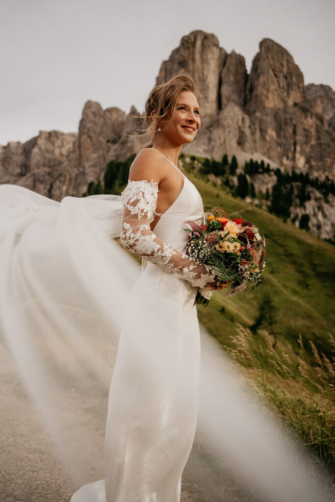 Bride in mountain setting with flowing veil.