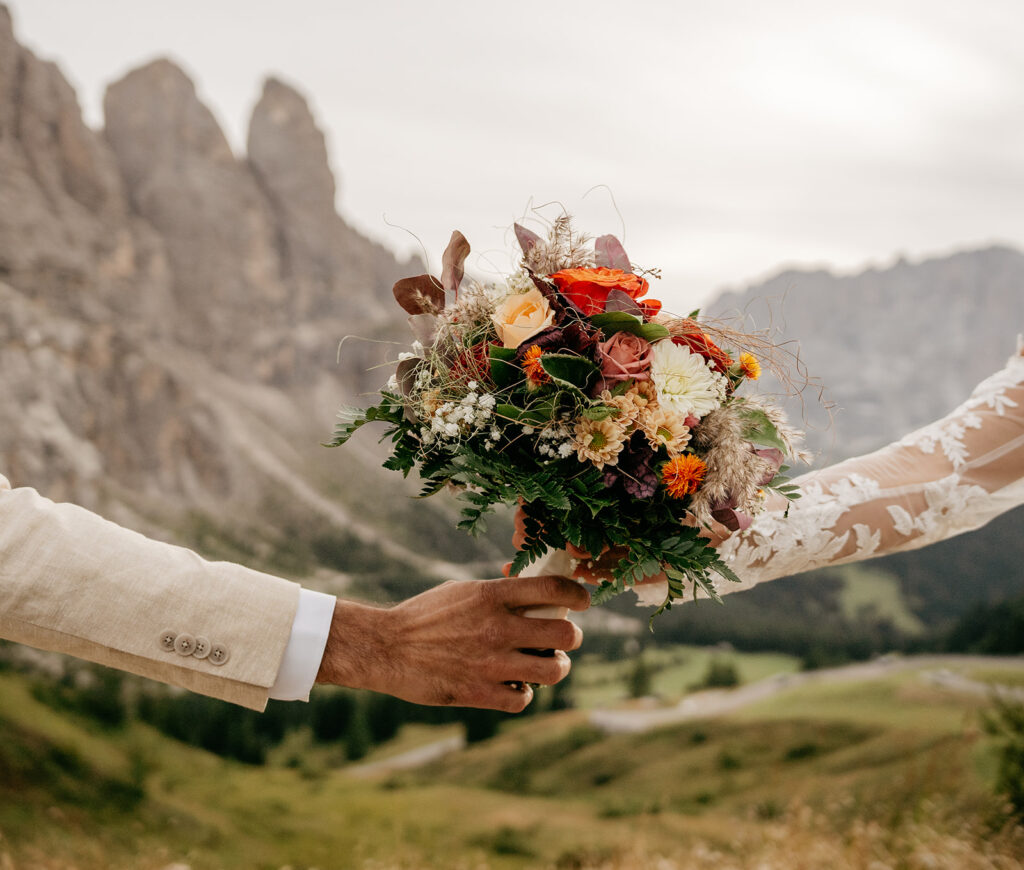 Couple exchanging bouquet in mountain landscape.