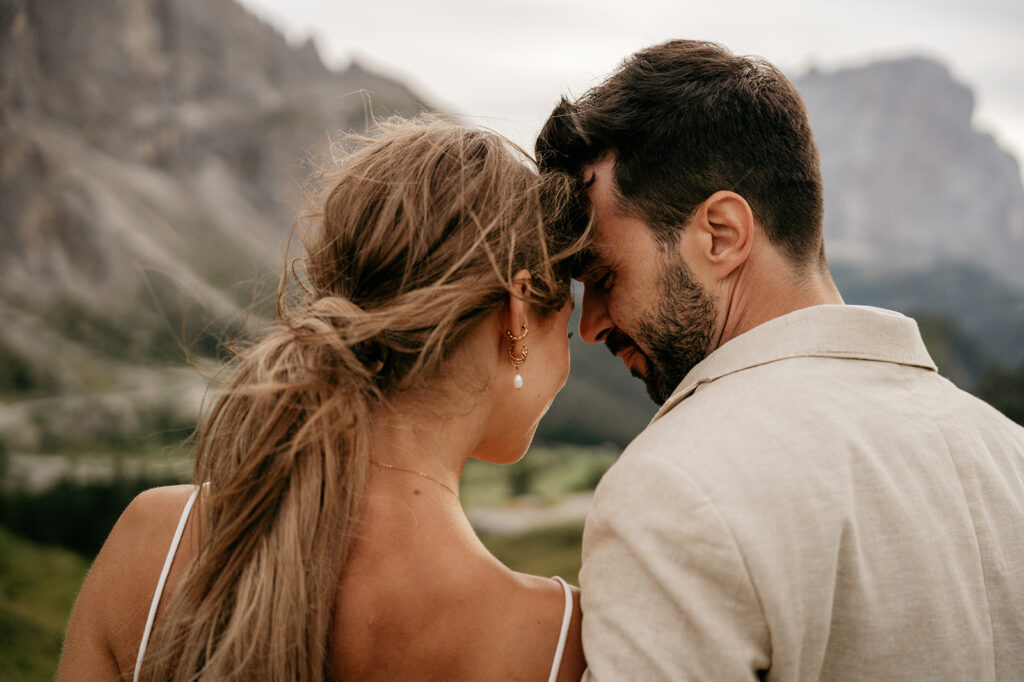 Couple embracing against mountainous landscape backdrop.