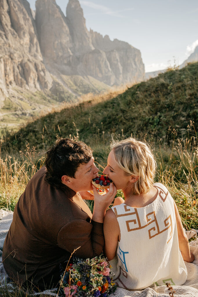 Couple sharing fruit tart in scenic mountain view.