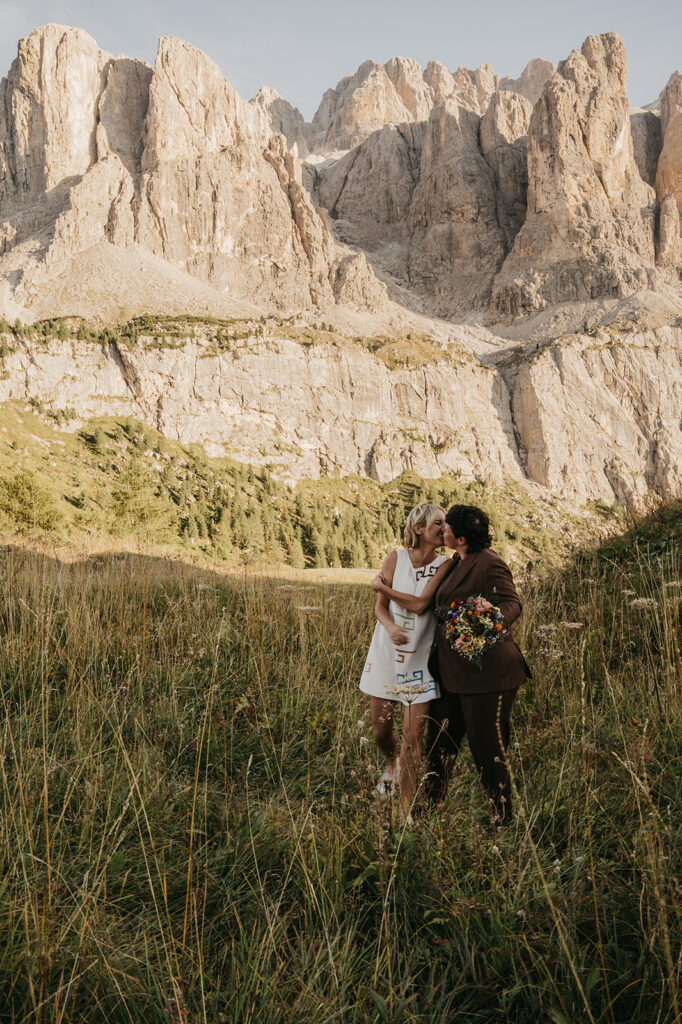 Couple embraces in mountain meadow landscape.