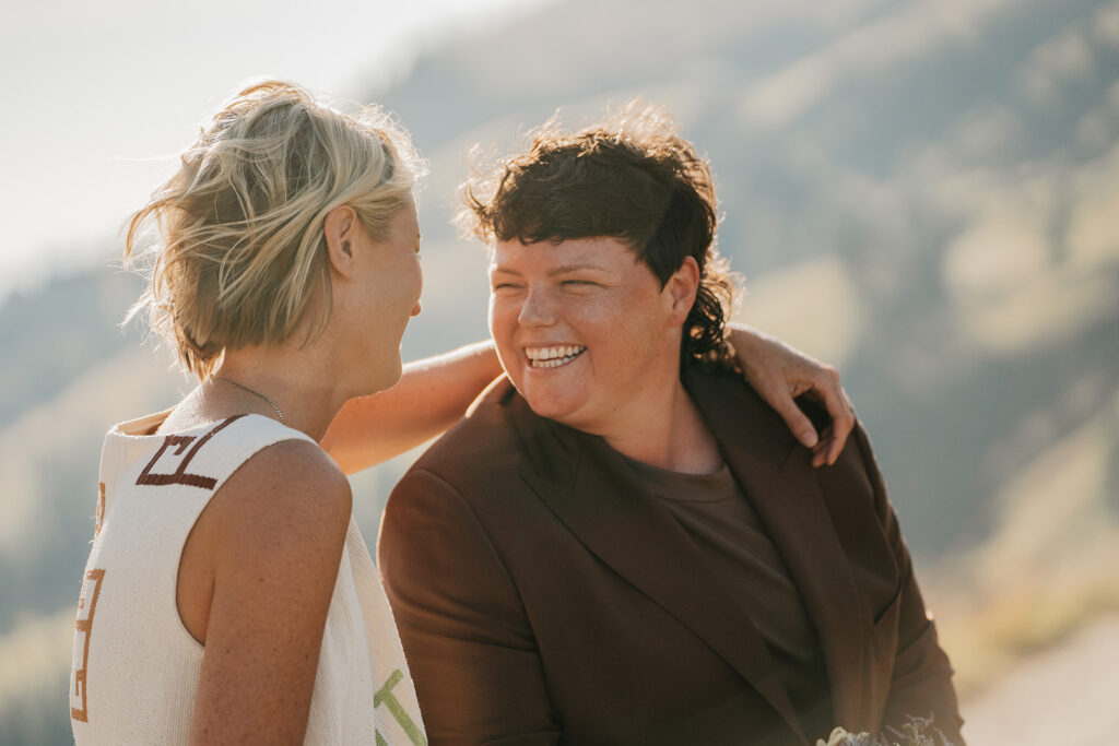 Two people smiling outdoors in sunlight.