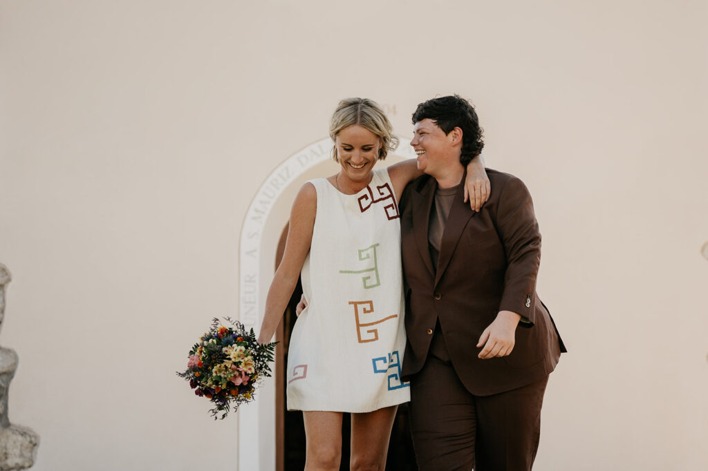 Couple smiling, holding bouquet, dressed formally.