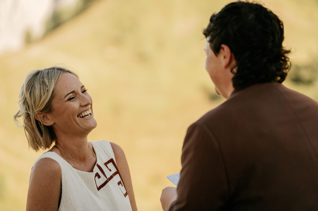 Two people smiling outdoors in natural setting.