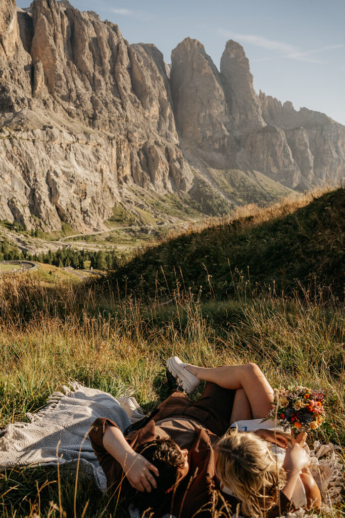 Couple relaxing on grass with mountain view.