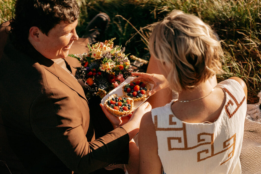 Couple enjoying fruit tarts and flowers outdoors.