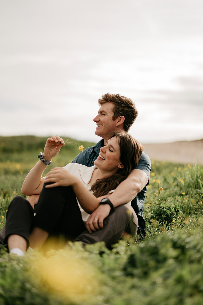 Couple sitting happily in sunny field.