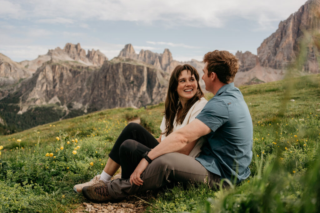 Couple sitting in mountain meadow, smiling