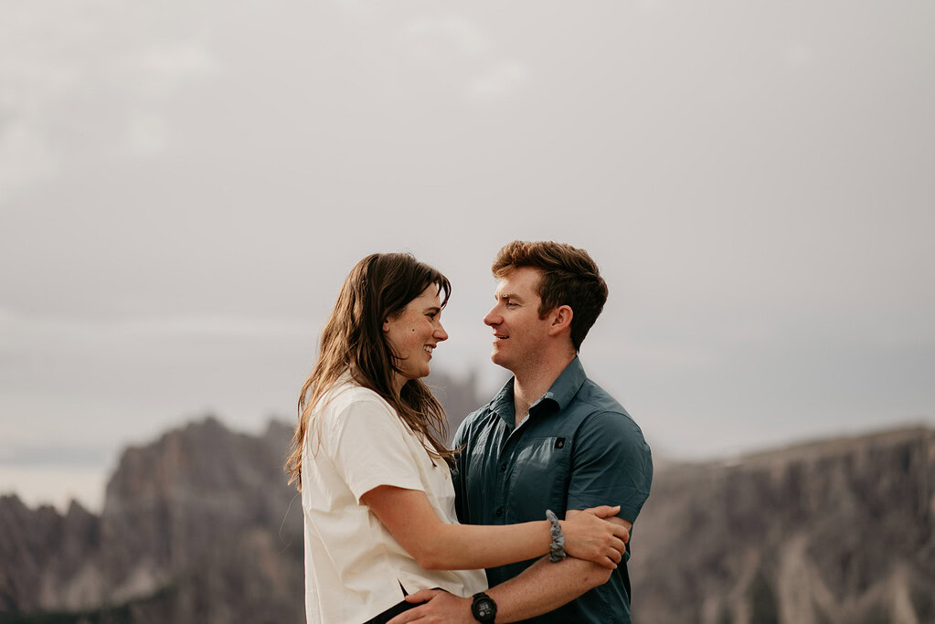 Couple smiling in mountainous landscape.