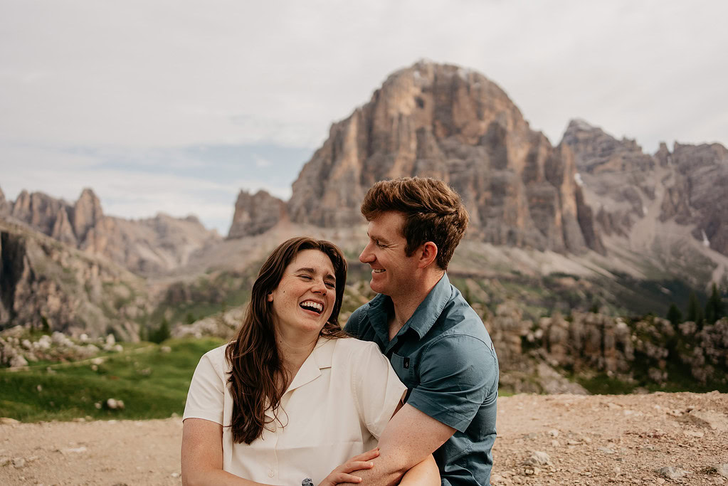 Couple laughing in scenic mountain landscape.