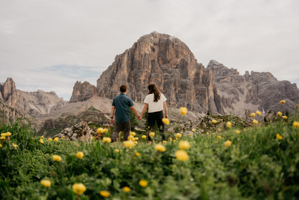 Couple holding hands near a mountain landscape.