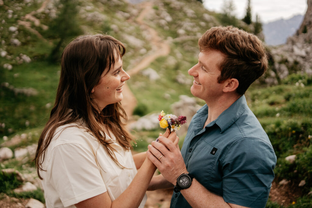 Couple sharing flowers in scenic outdoor setting.