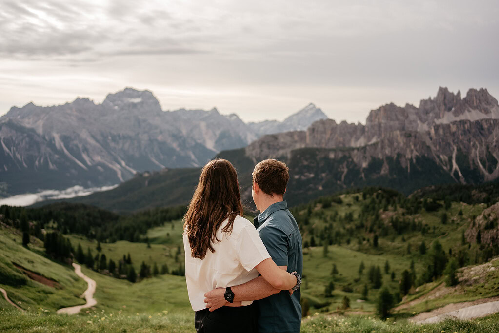 Couple embracing, overlooking scenic mountain landscape.