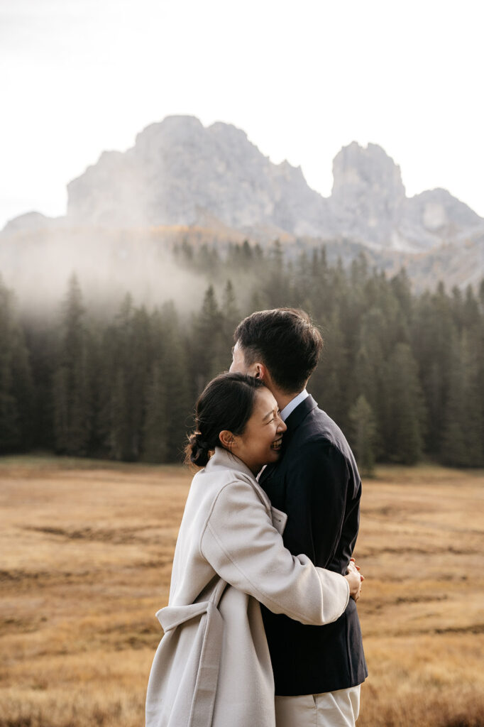 Couple embracing in a scenic mountain meadow.