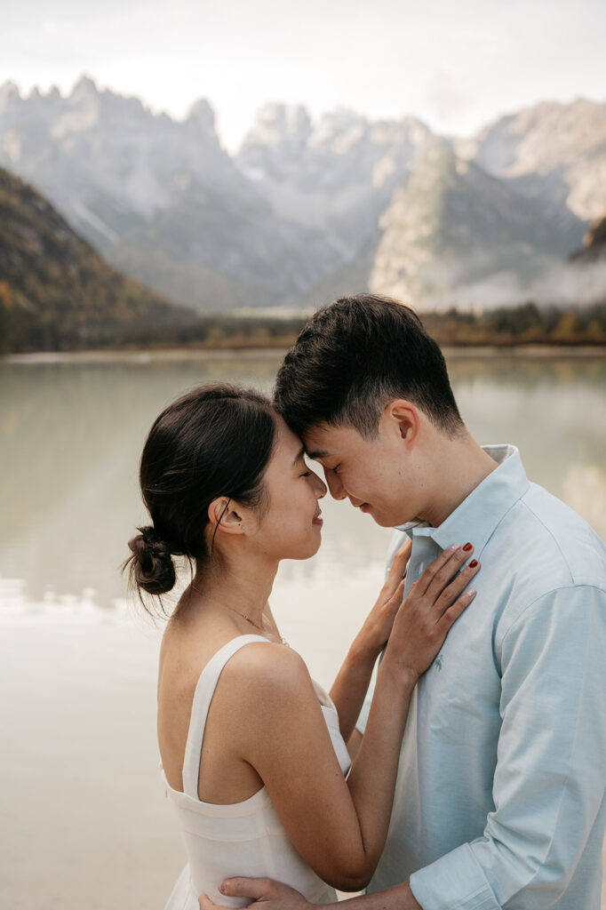 Couple embracing by a serene mountain lake.