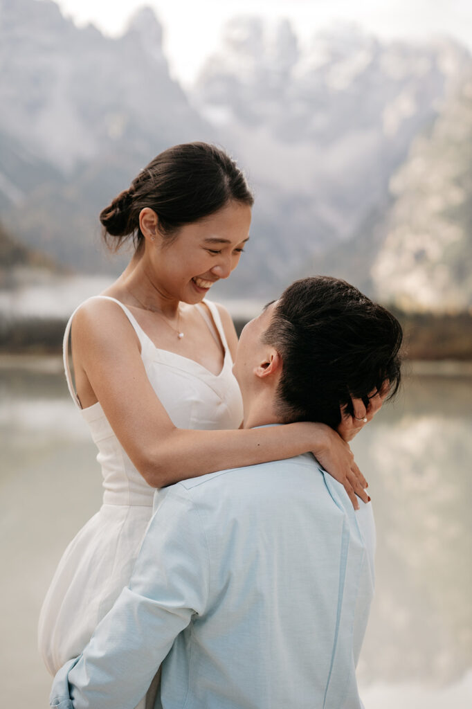 Couple embracing by the lake, smiling happily.