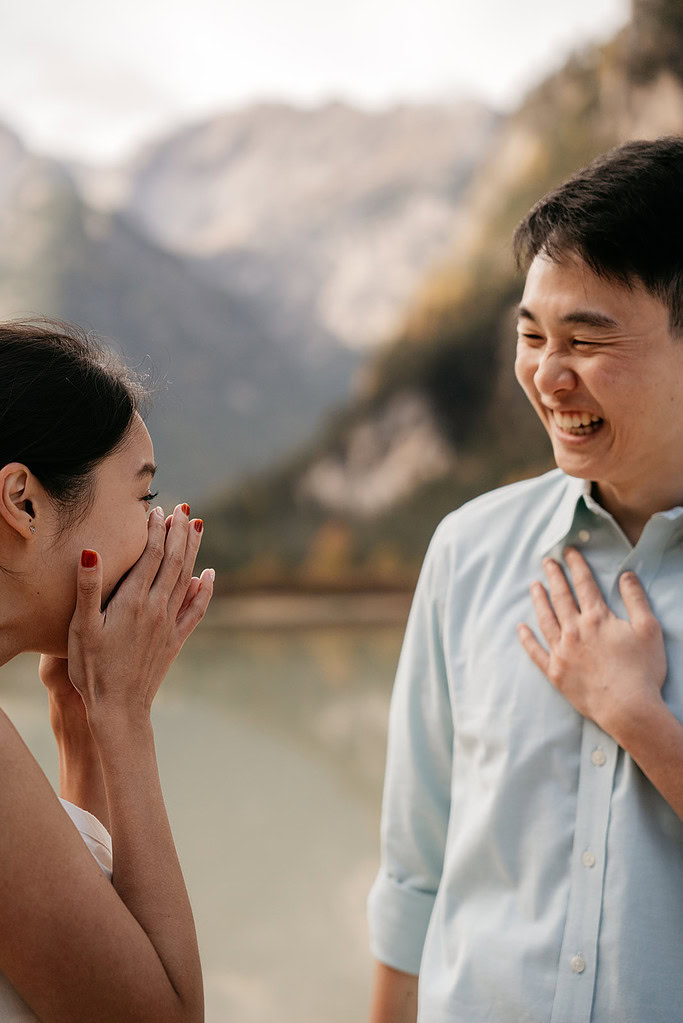 Couple laughing together outdoors by lake.