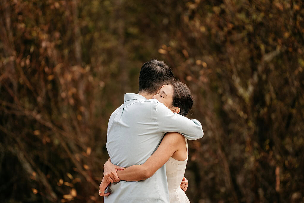 Couple embraces outdoors in a loving hug.