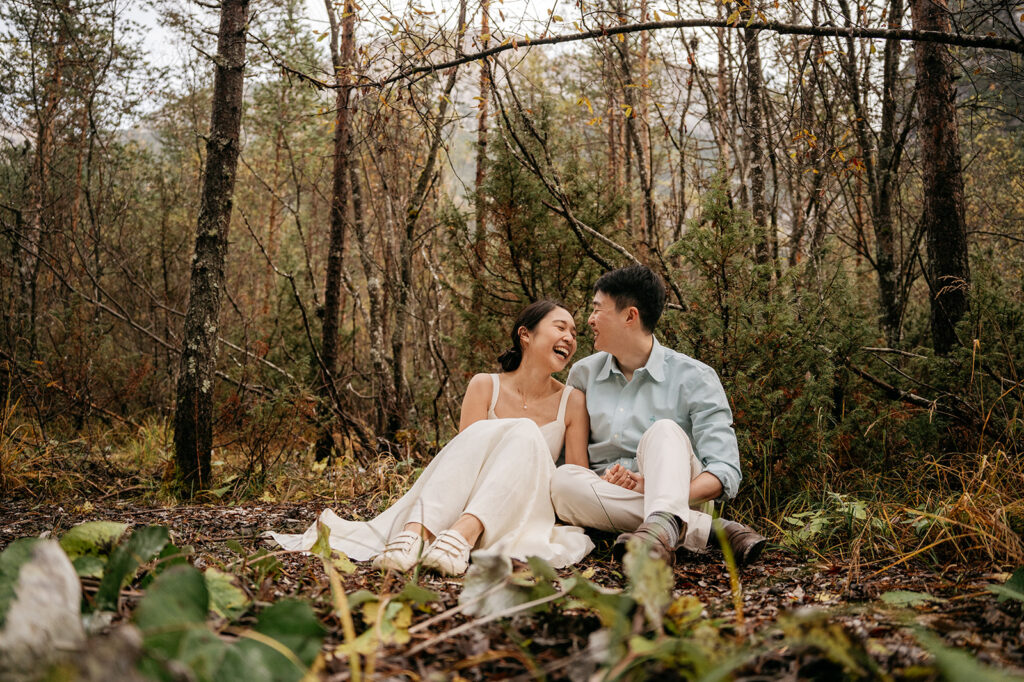 Couple laughing together in a forest setting.