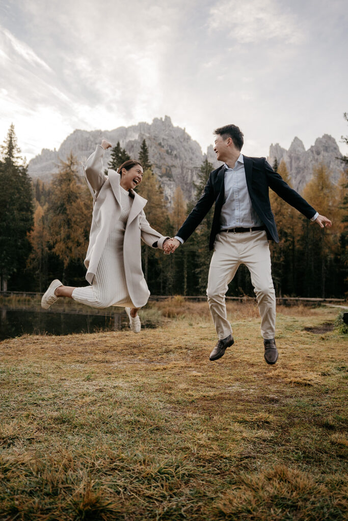 Couple joyfully jumping in scenic mountain landscape.