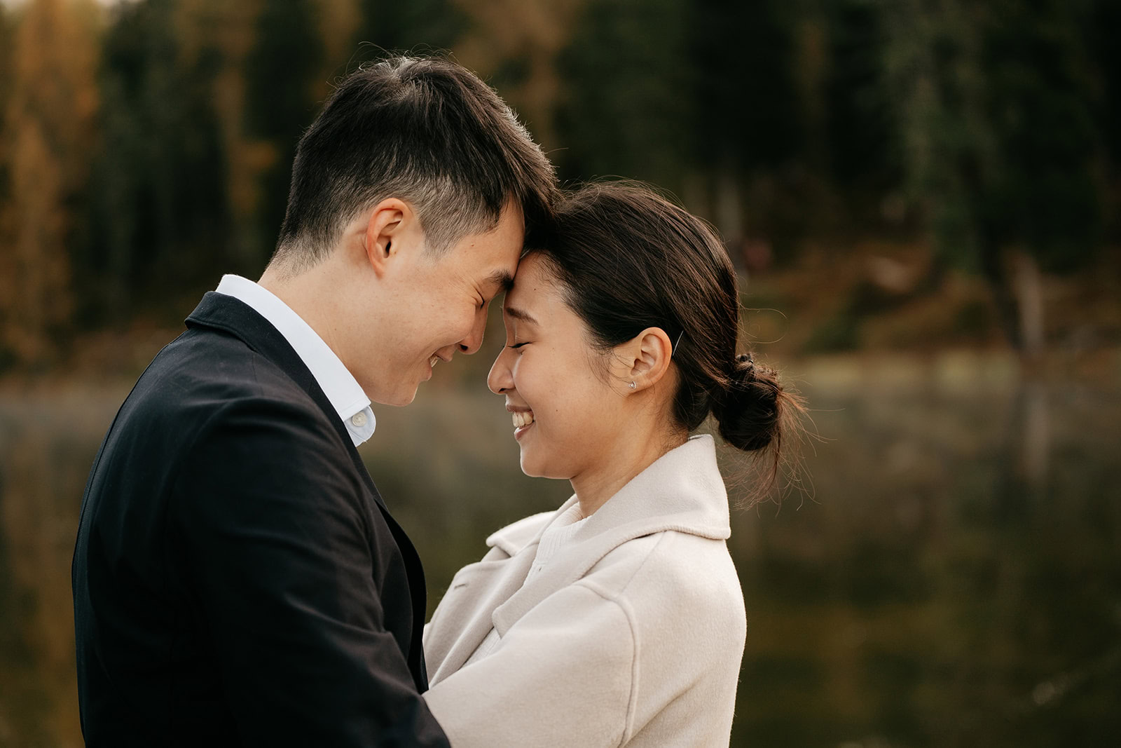 Smiling couple embracing outdoors by the lake.