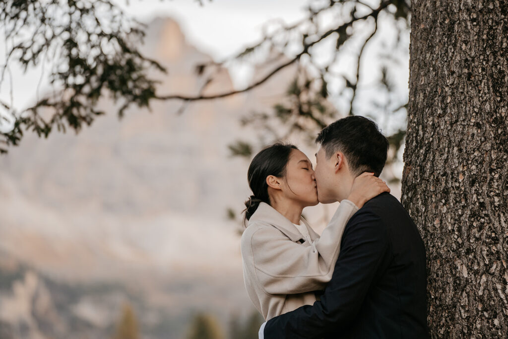 Couple kissing by a tree in nature.