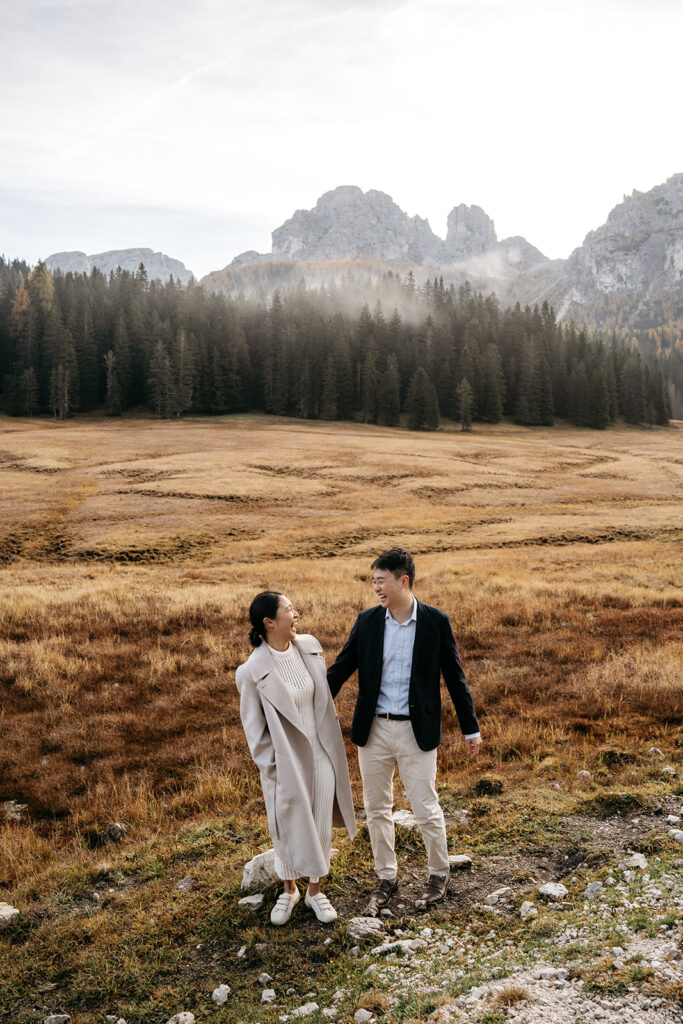 Couple smiling in scenic mountain landscape.