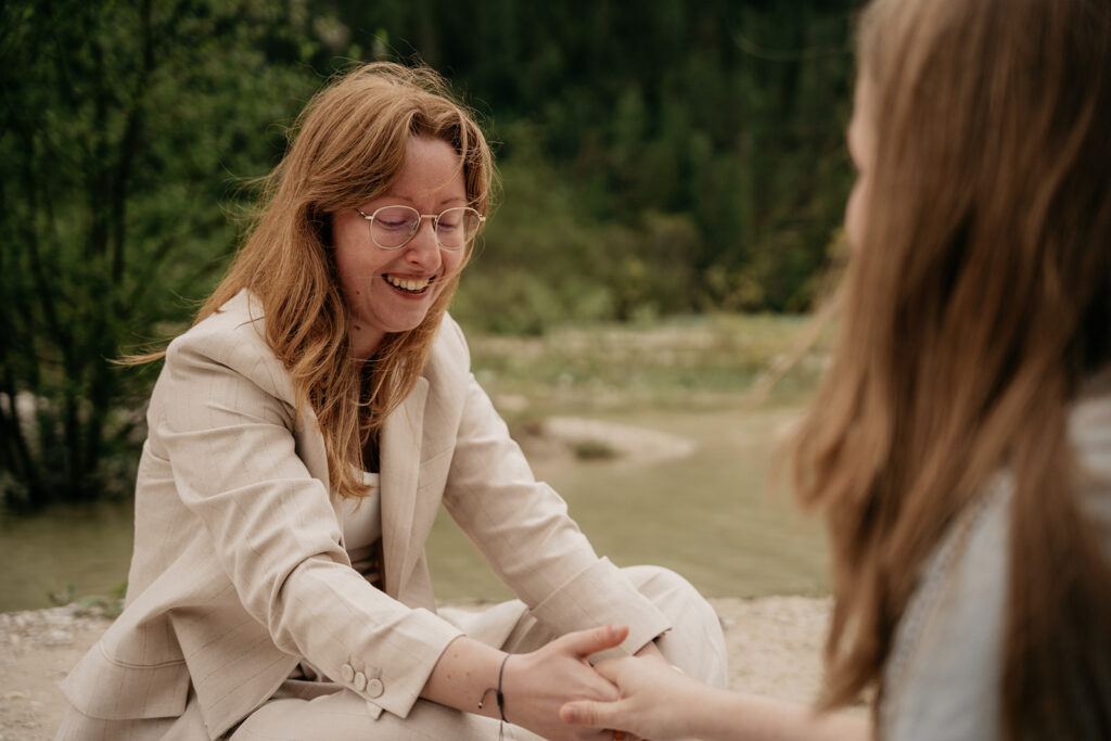 Laughing woman outdoors holding hands with another person.