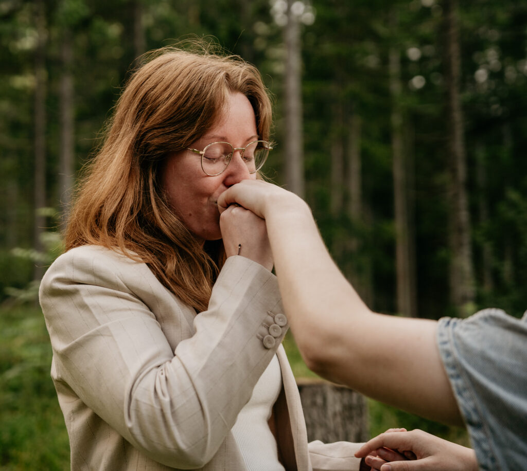 Person kissing hand in forest setting