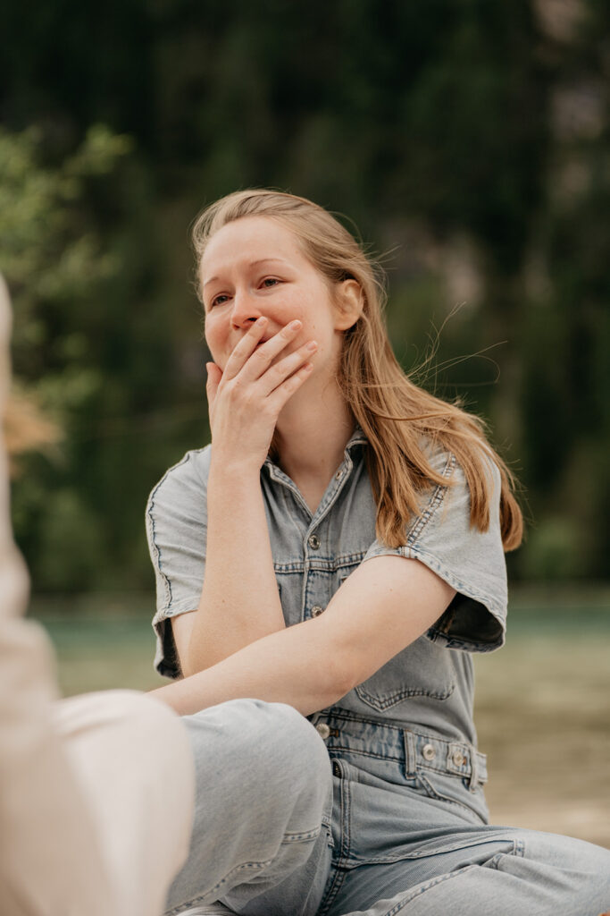 Woman smiling, covering mouth in surprise