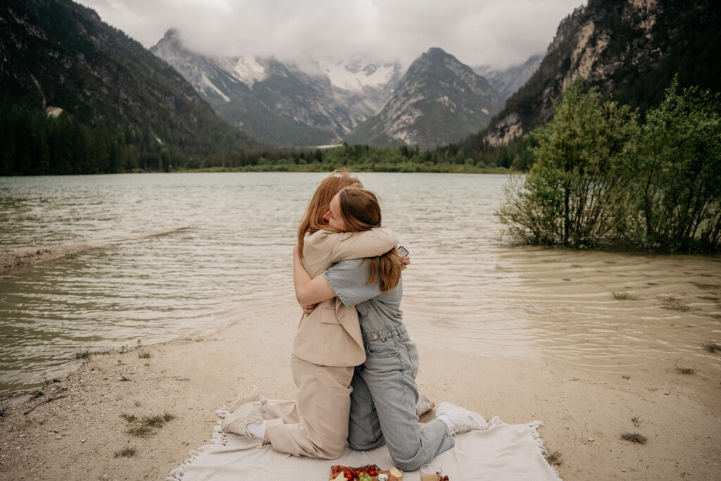 Friends hugging by a scenic mountain lake