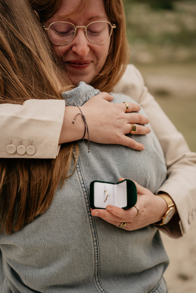 Couple hugging with engagement ring box