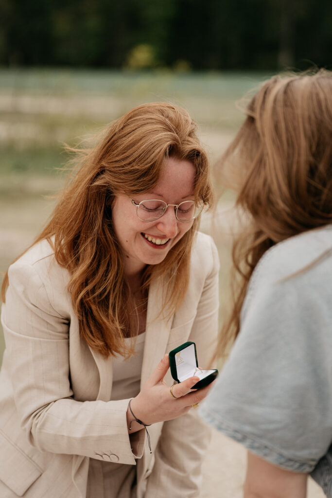 Woman proposing with engagement ring outdoors.