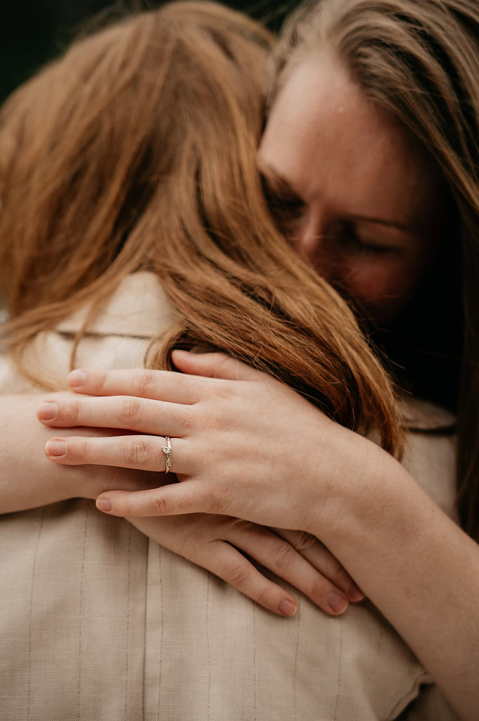 Close embrace highlighting engagement ring on hand.