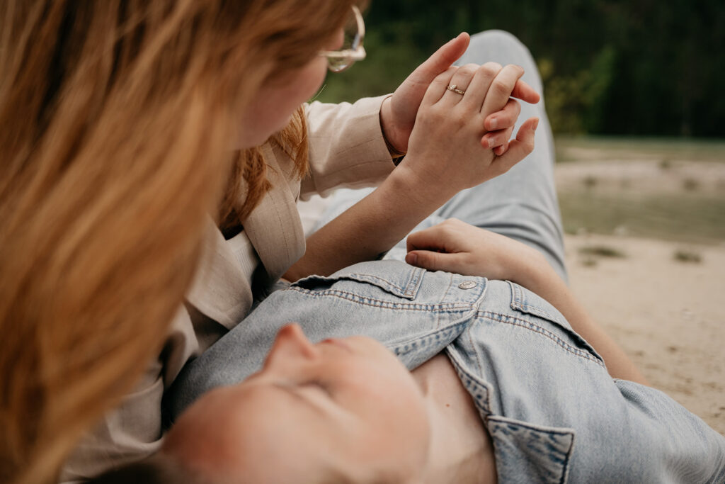 Couple holding hands outdoors, ring visible.