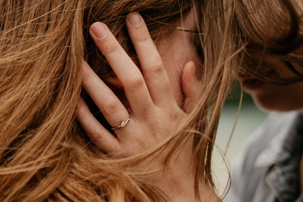 Woman wearing engagement ring, touching partner's face.