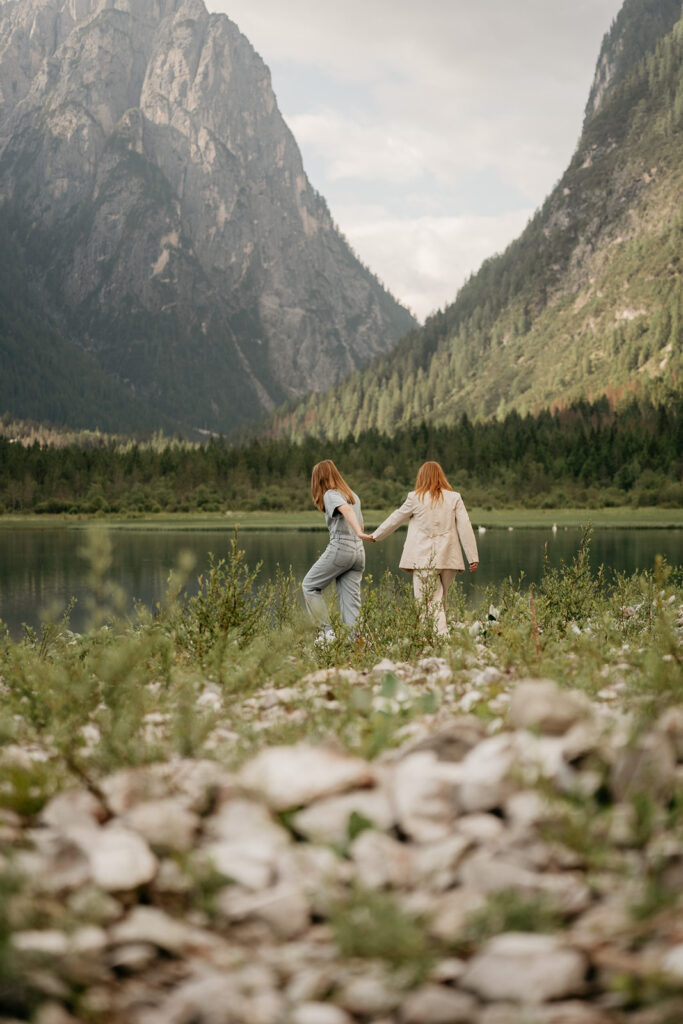 Two people walking by a mountain lake.